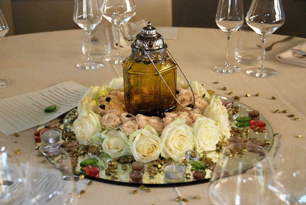 A centerpiece inspired by The Count of Monte Cristo, by Alexandre Dumas, with an amber coloured lamp inside a ring of white and pink roses