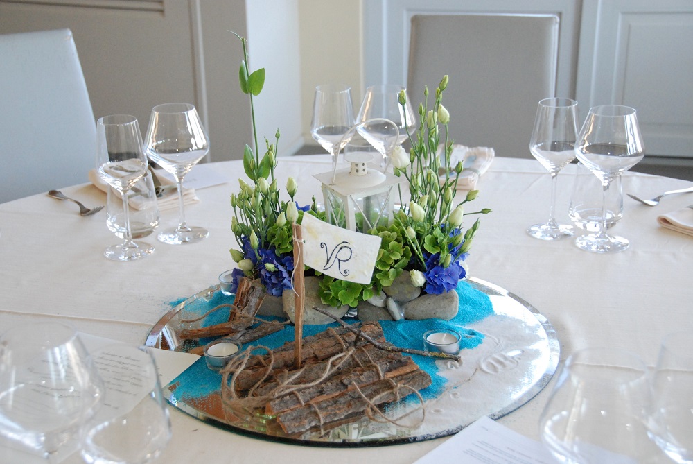 A centerpiece inspired by Tom Sawyer, by Mark Twain, with a raft made of bark on white and light blue sand.