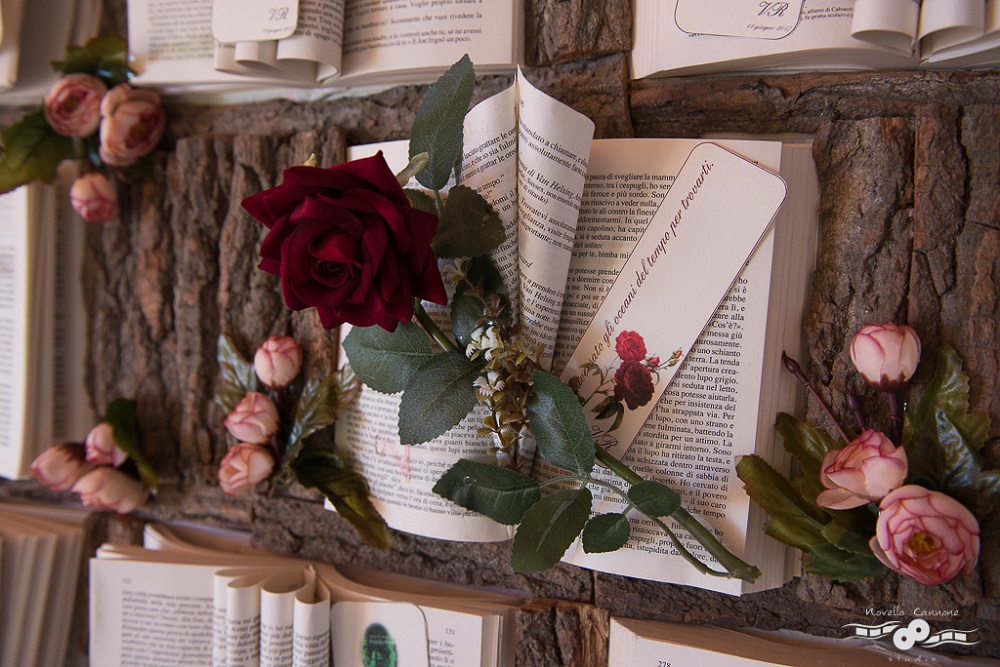 Close up of a Tableau de Mariage made with victorian literature, with a red rose on top, on a sheet of tree bark